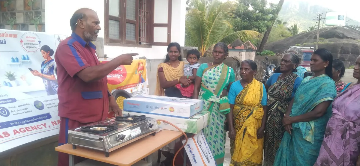 Sakthi Gas staff member showing a two-burner gas stove to a group of customers